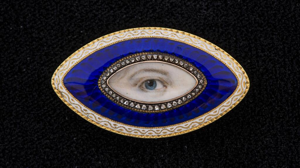 A gold oval Lover’s Eye brooch with a band of diamonds within a blue glass guilloche border surrounded by white enamel, 1890 20211102_Lovers Eyes book insert.jpg